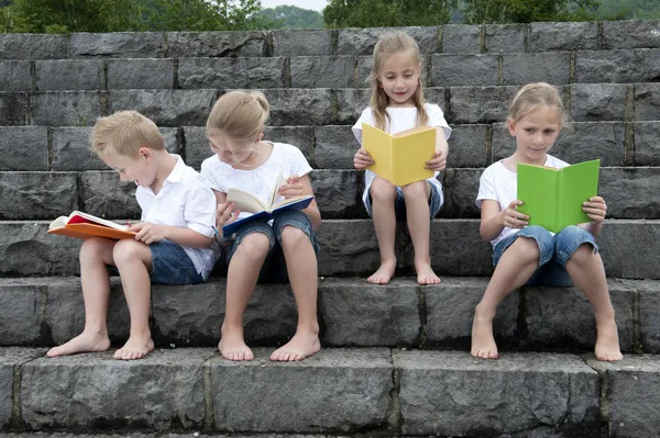 Férias de verão: crianças com um livro sentado ao ar livre em escadas — Fotografia de Stock