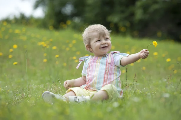 Bahçedeki çiçekleri ile oynarken oturmuş toddler — Stok fotoğraf