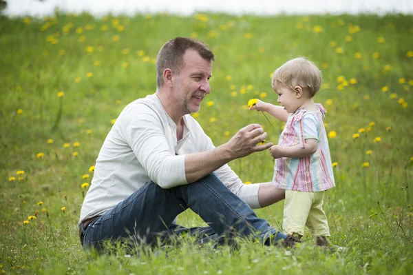 Tout-petit assis dans le jardin, jouant avec les fleurs — Photo