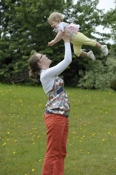 Moeder haar baby gooien in de lucht, buitenshuis — Stockfoto