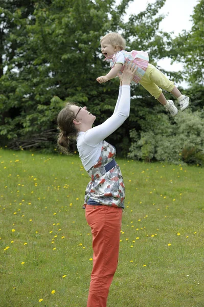 Moeder haar baby gooien in de lucht, buitenshuis — Stockfoto