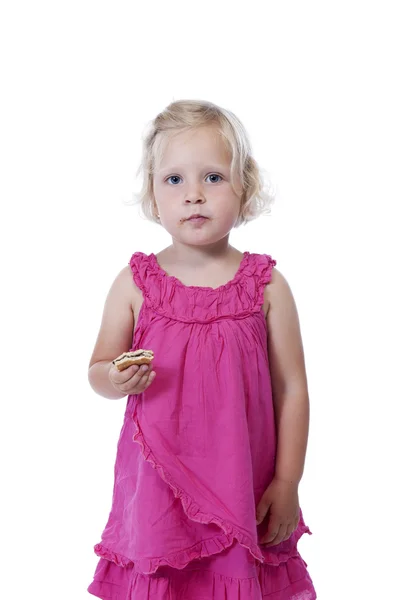 Petite fille en rose manger un biscuit, isolé sur blanc — Photo