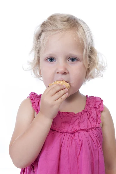 Bambina in rosa che mangia un biscotto, isolata su bianco — Foto Stock