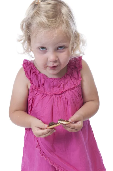 Little girl in pink eating a biscuit, isolated on white — Stock Photo, Image