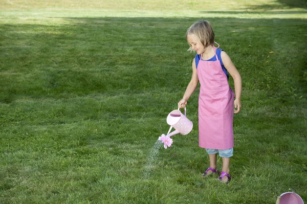 Liten flicka med vattenkanna i trädgården — Stockfoto