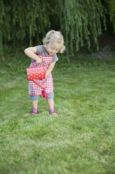 Liten flicka med vattenkanna i trädgården — Stockfoto