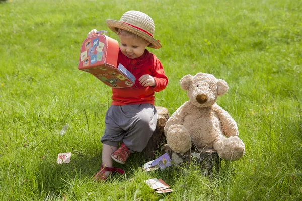 Ona bir oyuncak ayı ile bahçede oturan küçük yürümeye başlayan çocuk — Stok fotoğraf