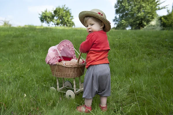 Kleines Kleinkind spielt mit Kinderwagen im Freien — Stockfoto