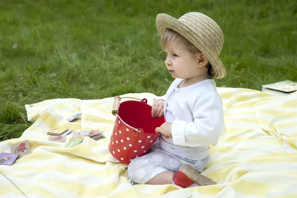 Малыш бледнеет в саду с красным ведром — стоковое фото