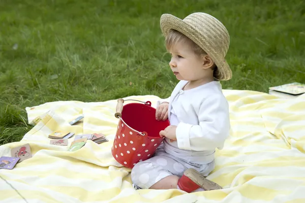 Toddler palying in the garden with a red bucket — Stock Photo, Image