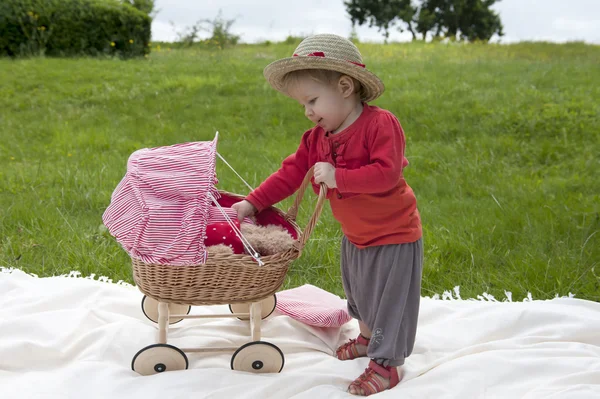 Little toddler playing with a pram outdoors — Stock Photo, Image