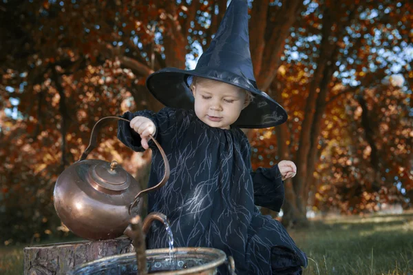 Little halloween witch with couldron outdoors — Stock Photo, Image