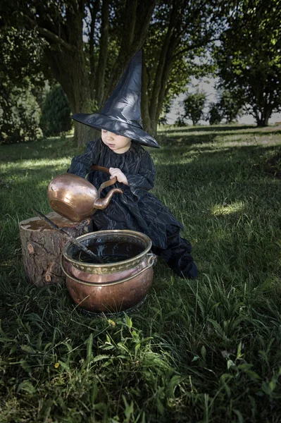 Kleine halloween heks met couldron outdoors — Stockfoto