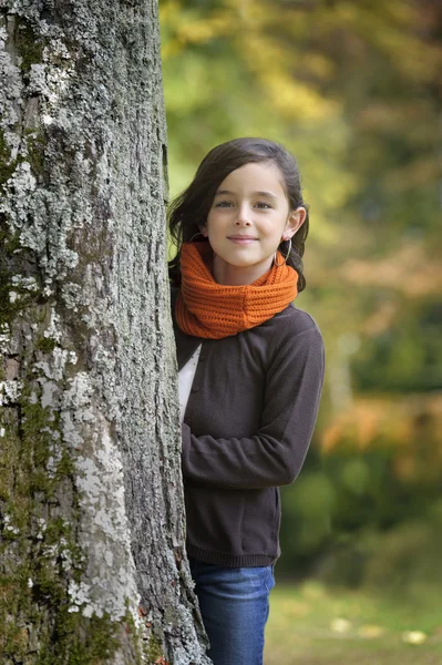 Flickan tittar bakom ett träd — Stockfoto