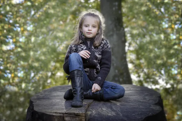 Flicka sittande på en stam i parken — Stockfoto