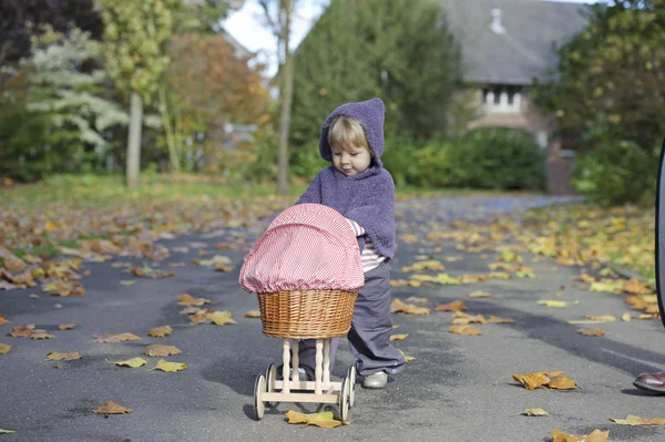 Niña jugando con un cochecito en un parque — Foto de Stock