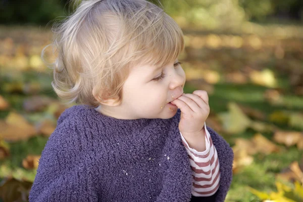 Klein meisje een koekje eten buitenshuis — Stockfoto