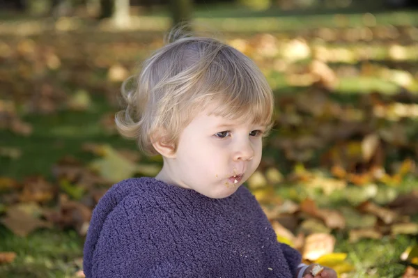 Little girl eating a biscuit outdoors — Stock Photo, Image