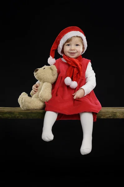 Little girl with christmas hat and teddy bear — Stock Photo, Image
