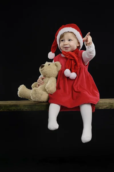 Маленька дівчинка з різдвяним капелюхом і плюшевим ведмедем — стокове фото