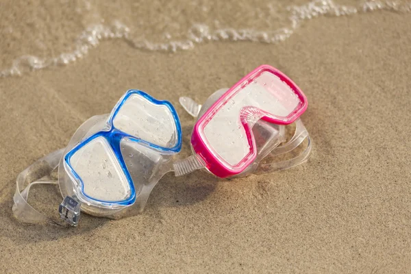 Summer time: Red and blue gogles on the sand washed by the ocean — Stock Photo, Image