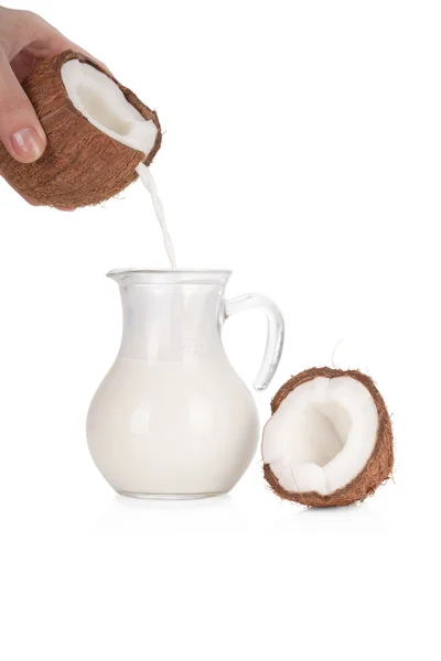 Woman's hand pouring coconut milk into a jar isolated on white — Stock Photo, Image