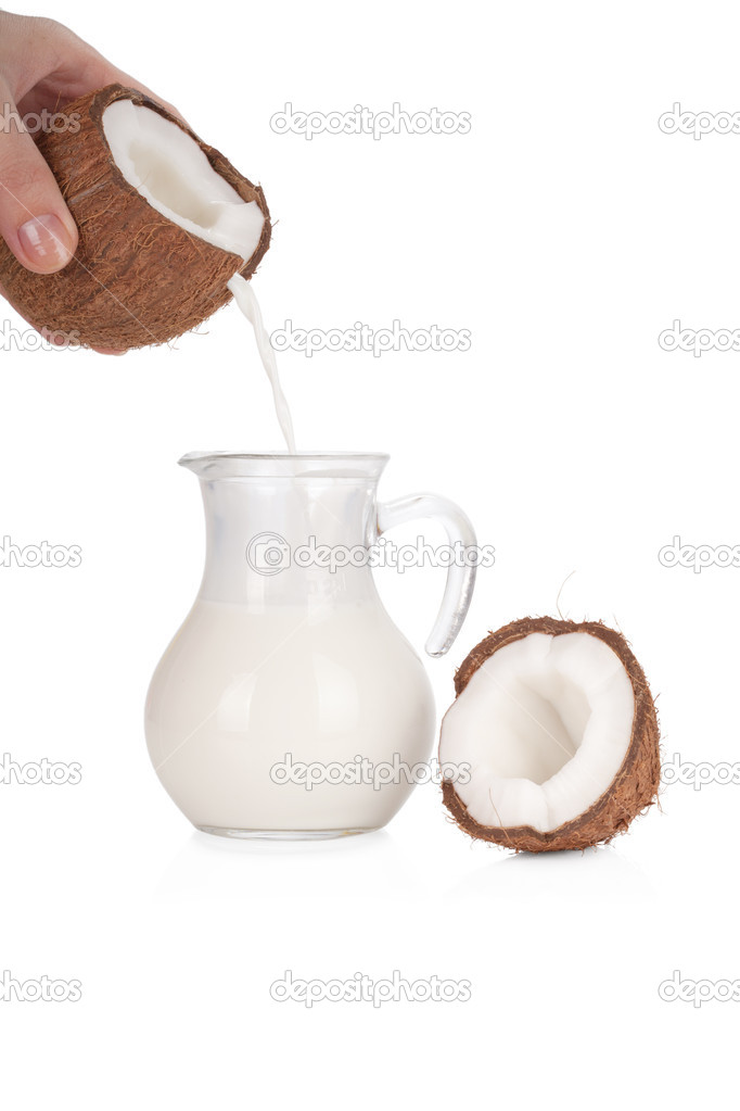 Woman's hand pouring coconut milk into a jar isolated on white