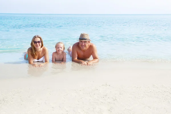 Happy family laying on the sand enjoying the ocean — Stock Photo, Image