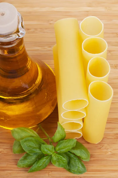 Каннеллони с оливковым маслом в стеклянной бутылке и свежим базиликом — стоковое фото