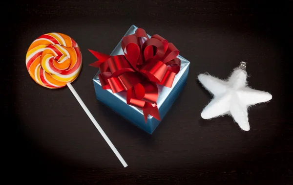 Blue gift box, candycane and white christmas star on black woode — Stock Photo, Image