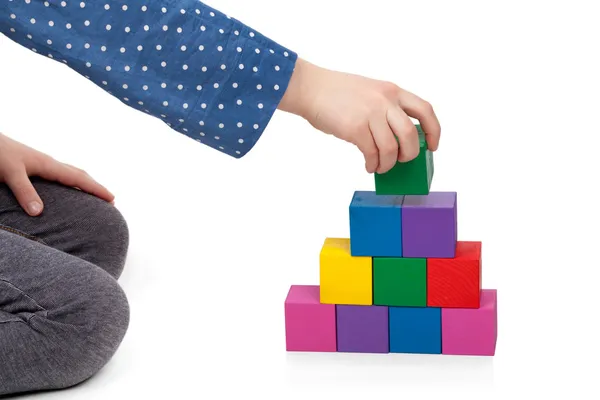 La mano del bambino costruisce una torre di mattoni isolata su sfondo bianco — Foto Stock