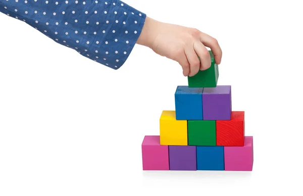 La mano del bambino costruisce una torre di mattoni isolata su sfondo bianco — Foto Stock