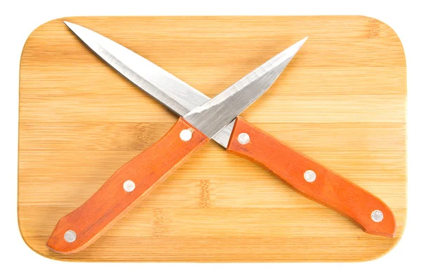 Cuchillos de cocina cruzados sobre tabla de cortar — Foto de Stock