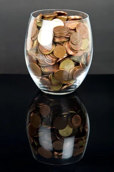Münzen im Glas über Schwarz — Stockfoto