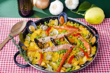 Çeşitli deniz ürünleri paella, midye, midye, karides, bezelye ve limonla süslenmiş bir masa..