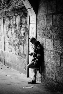 PONTEVEDRA, SPAIN - JULY 20, 2021: Black and white photo of a man consulting his smartphone under a stone arch in the historic center of the city.