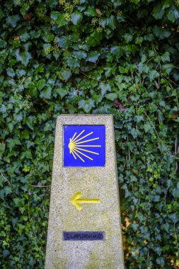 Granite post with the yellow icon on a blue background, indicating the Camino de Santiago in Galicia (Spain)