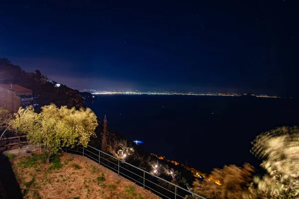 Top view of the Mediterranean sea at night time with city lights on background