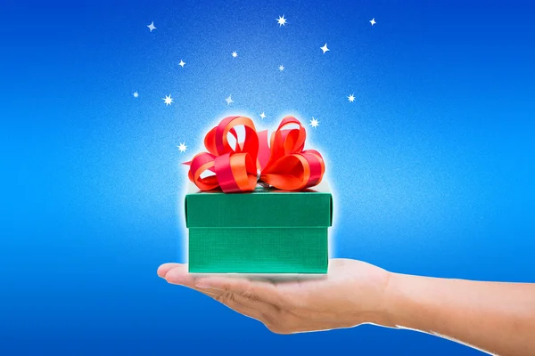 Elle mavi zemin üzerine yeşil hediye kutusu — Stok fotoğraf