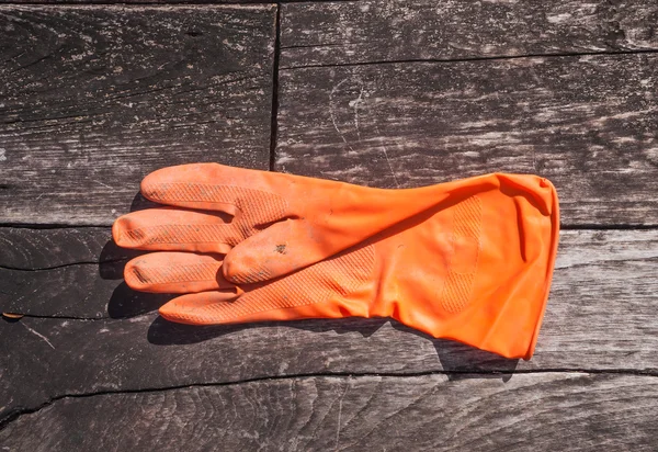 Ahşap zemin üzerinde turuncu lastik eldiven — Stok fotoğraf
