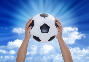 Futbol topu elinde mavi gökyüzü ve lightray arka plan