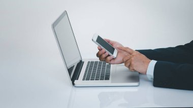 İşadamı dizüstü bilgisayarlı akıllı telefon kullanıyor. İş ve teknoloji kavramı.