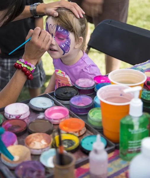 Young girl getting her face painted as a butterfly Royalty Free Stock Images