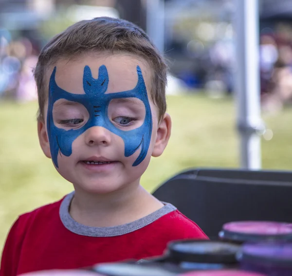 Young boy getting blue face paint Stock Photo