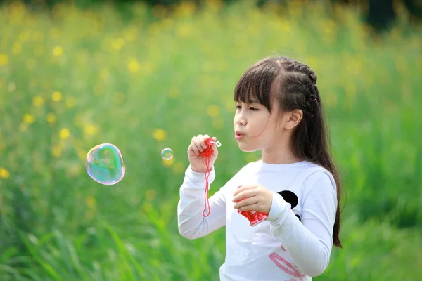 Porträtt av vacker glad liten flicka i ett fält av gula blommor — Stockfoto