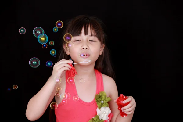 Маленькая азиатка надувает мыльные пузыри. — стоковое фото