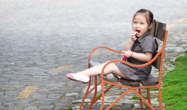 Милая улыбающаяся маленькая девочка сидит на скамейке — стоковое фото