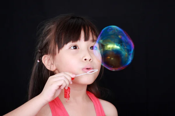 Šťastná dívka hrát s černým pozadím mýdlové bubliny, samostatný — Stock fotografie