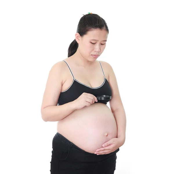 Pregnant woman hand holding a magnifying glass on her belly on w — Stock Photo, Image