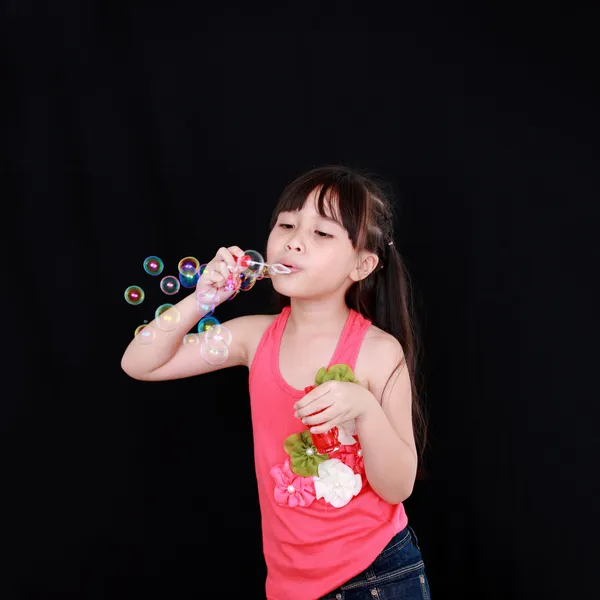 Gelukkig meisje spelen met zeepbellen geïsoleerd zwarte achtergrond — Stockfoto